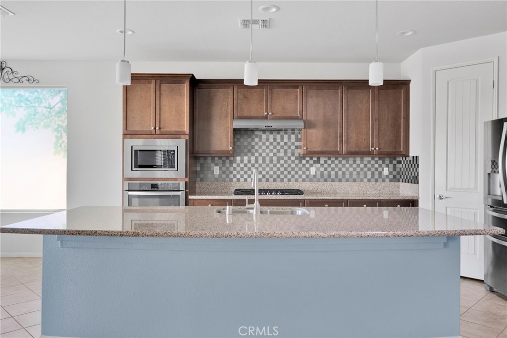 18968 Raven Street Apple Valley, CA 92308 - Photo 16 of 53 a kitchen with kitchen island granite countertop a sink a stove and cabinets