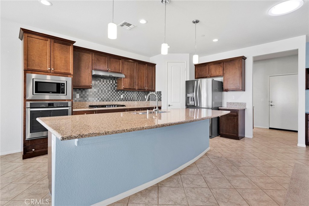 18968 Raven Street Apple Valley, CA 92308 - Photo 17 of 53 a large kitchen with kitchen island a large counter top stainless steel appliances and cabinets