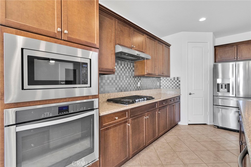 18968 Raven Street Apple Valley, CA 92308 - Photo 20 of 53 a kitchen with stainless steel appliances granite countertop a stove microwave and refrigerator