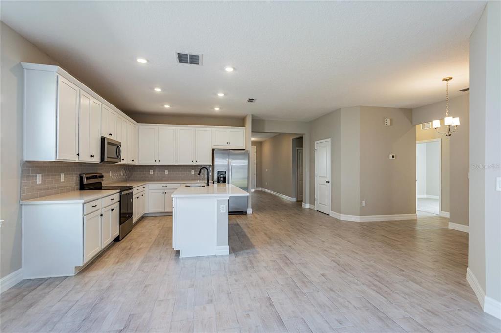 2031 Firethorn Loop Haines City, FL 33844 - Photo 3 of 20 a kitchen with a refrigerator and a stove top oven