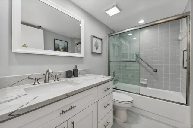 a bathroom with a granite countertop sink a toilet and shower