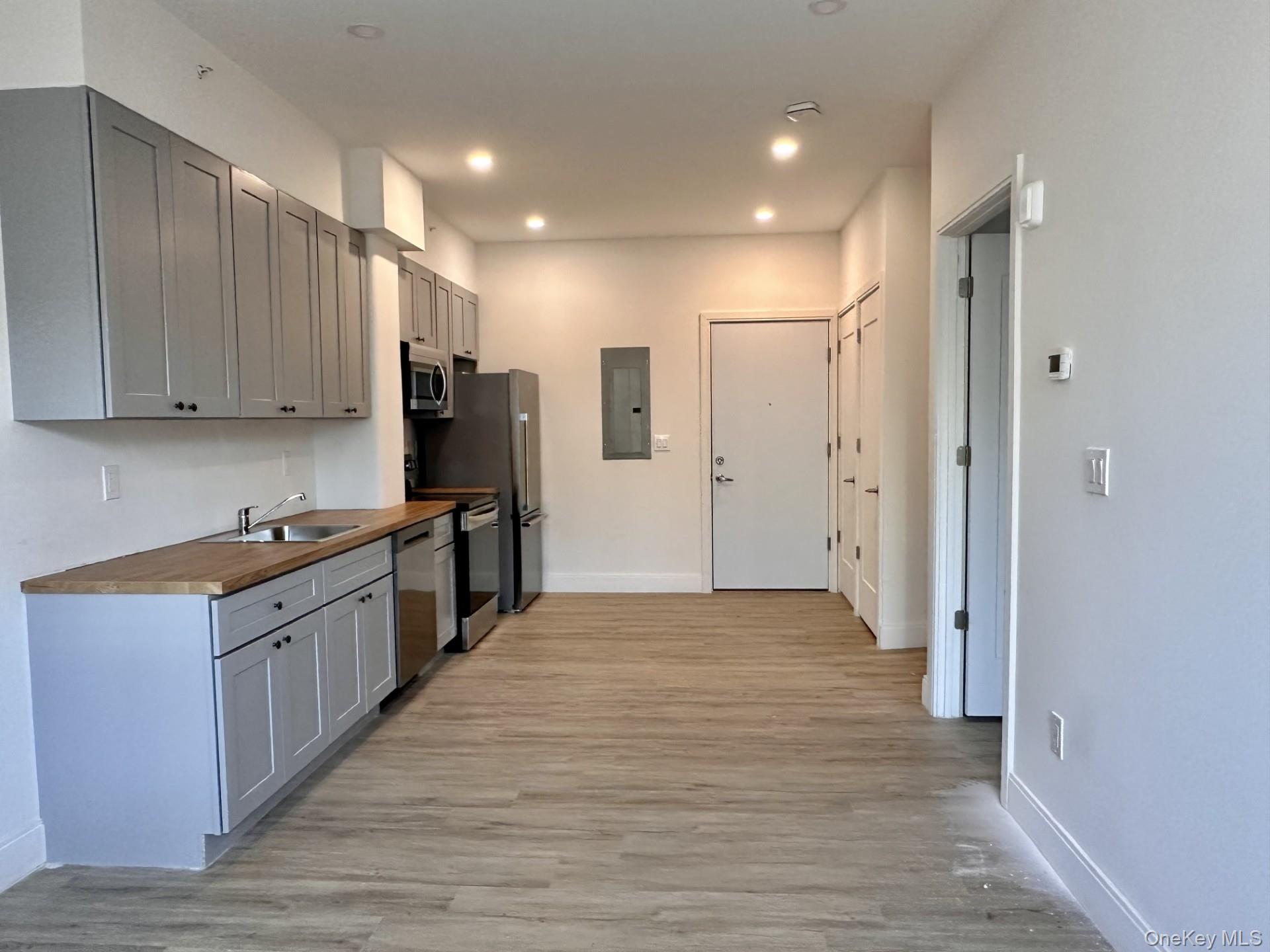 362 West Merrick Road, Unit 107 Valley Stream, NY 11580 - Photo 5 of 7 Kitchen with gray cabinetry, butcher block counters, stainless steel appliances, light wood-style flooring, and electric panel