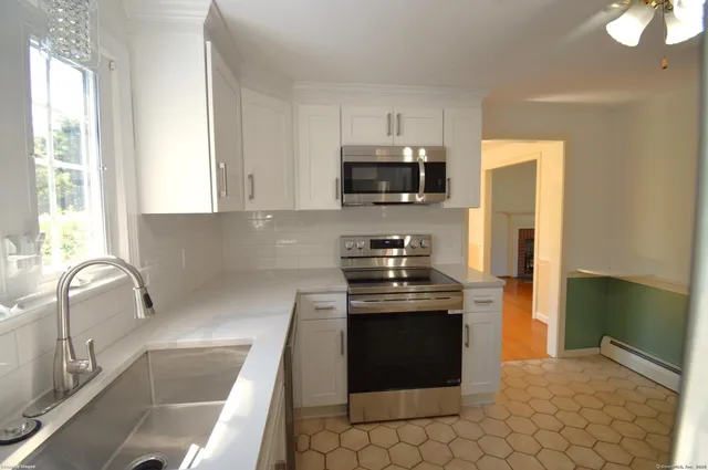 a kitchen with stainless steel appliances granite countertop a stove a sink and a microwave