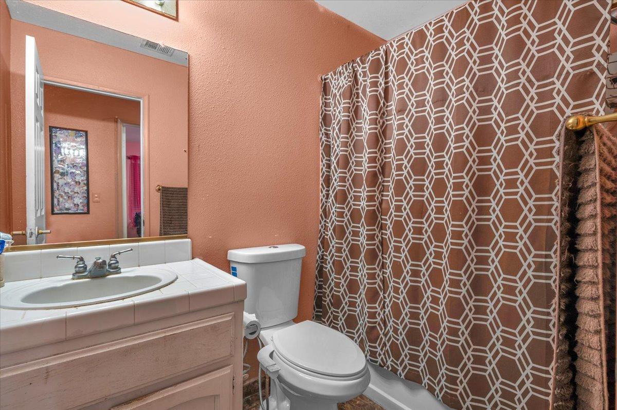 14440 West E Street Kerman, CA 93630 - Photo 9 of 13 a bathroom with a toilet a sink and a mirror