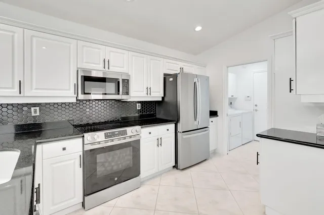 a kitchen with granite countertop white cabinets and black appliances