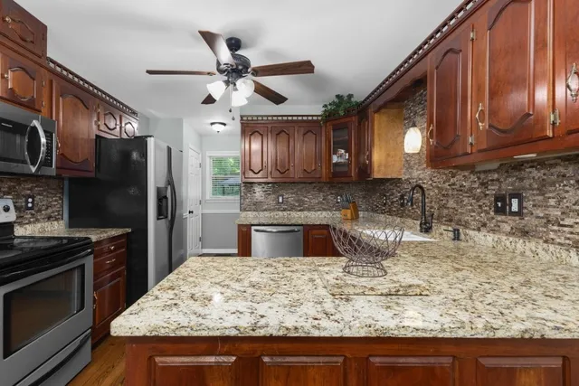 a kitchen with stainless steel appliances granite countertop a sink a stove top oven a refrigerator cabinets and wooden floor