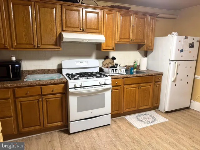 a kitchen with granite countertop wooden cabinets and white appliances