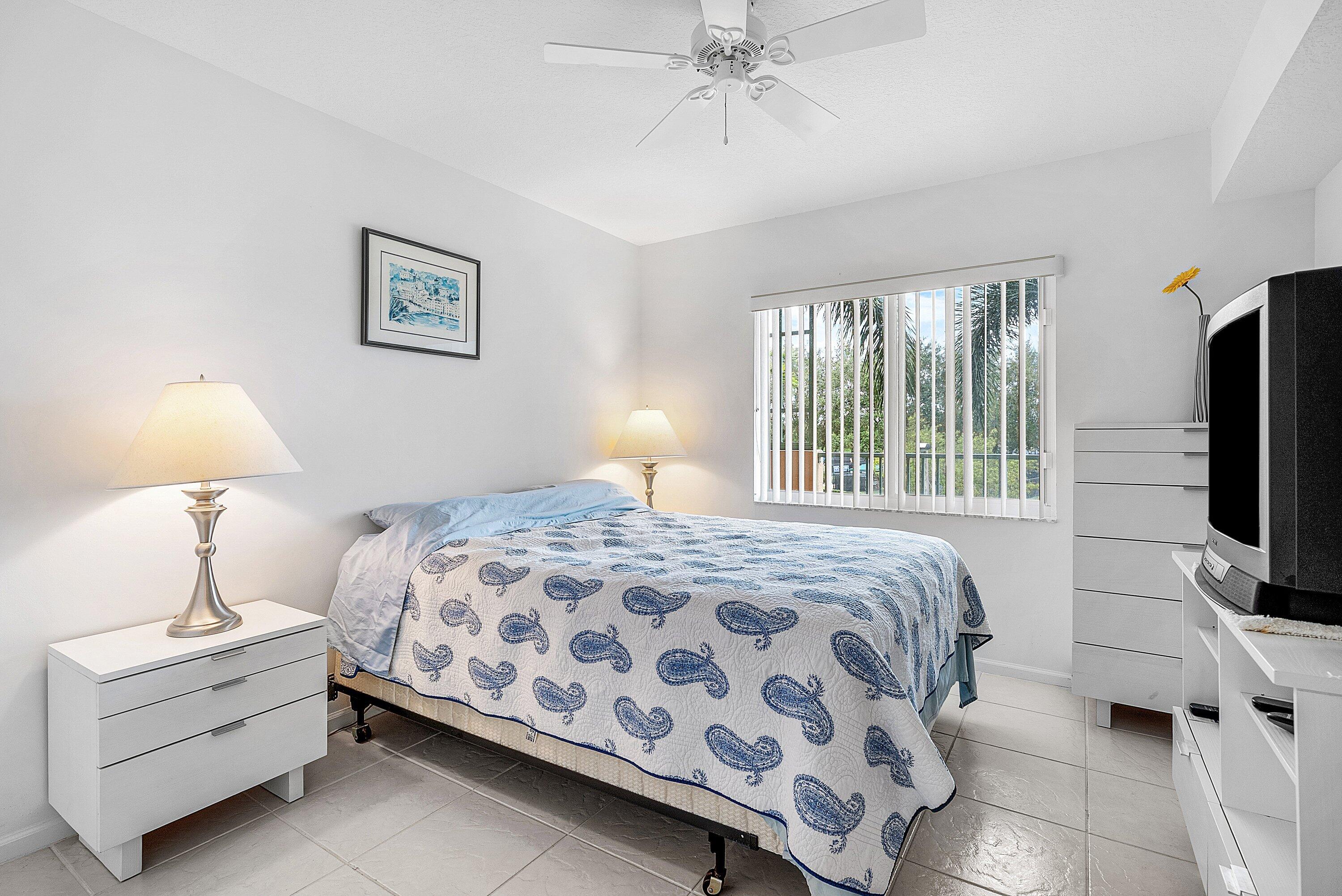 12560 Majesty Circle, Unit 303 Boynton Beach, FL 33437 - Photo 25 of 33 a bedroom with a bed and a chandelier