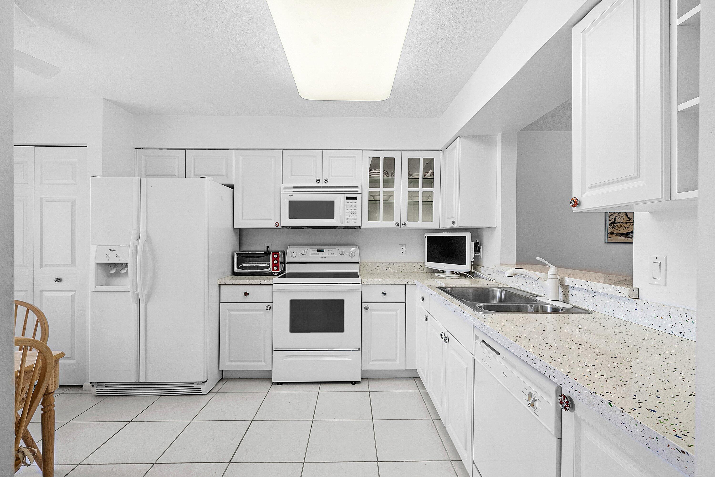 12560 Majesty Circle, Unit 303 Boynton Beach, FL 33437 - Photo 5 of 33 a kitchen with white cabinets and white appliances