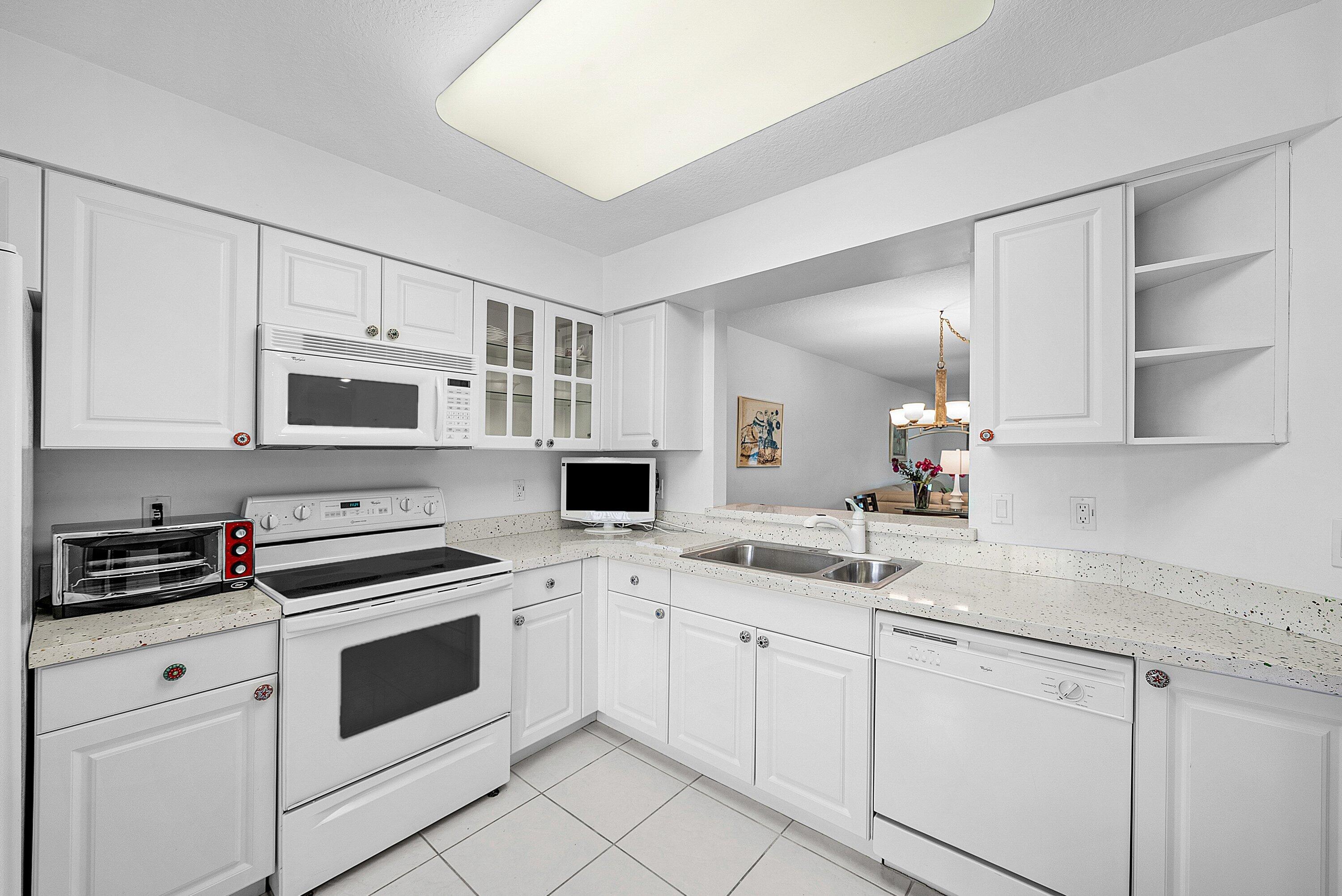 12560 Majesty Circle, Unit 303 Boynton Beach, FL 33437 - Photo 9 of 33 a kitchen with white cabinets and white appliances