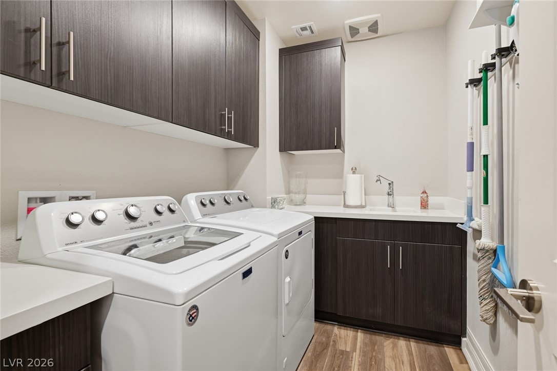 4246 Swift Street Las Vegas, NV 89135 - Photo 45 of 71 Laundry area with cabinet space, light wood-type flooring, and washing machine and dryer