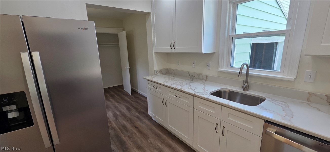 9964 East River Road Elyria, OH 44035 - Photo 16 of 45 Modern kitchen featuring white cabinetry, stone-finish countertops, stainless steel sink with gooseneck faucet, and wood-finish flooring looking into the flex room.