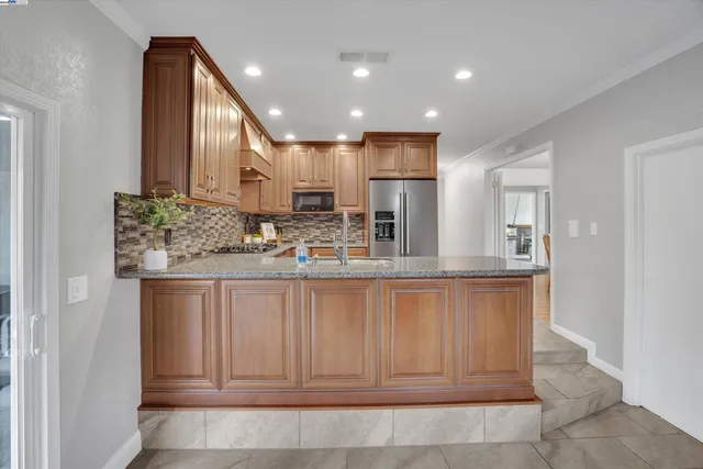 a kitchen with stainless steel appliances granite countertop a sink and a refrigerator