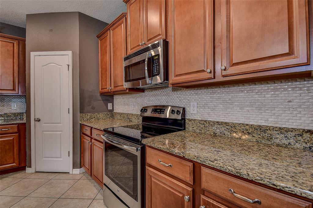 11656 Lake Boulevard New Port Richey, FL 34655 - Photo 11 of 55 a kitchen with stainless steel appliances granite countertop a sink a stove and a microwave