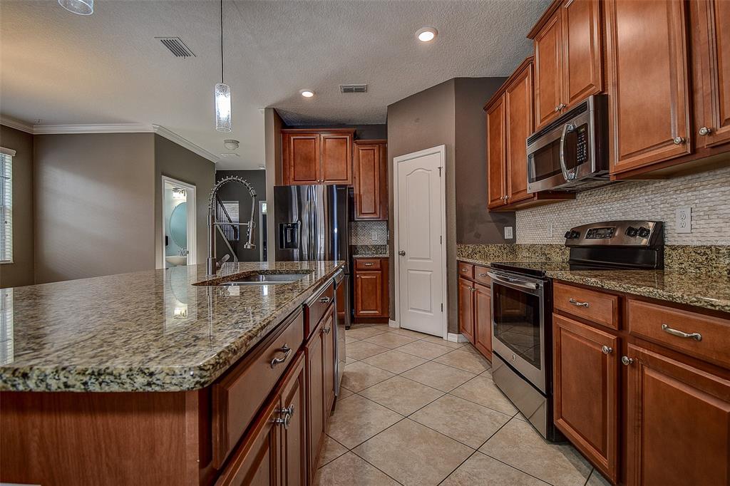 11656 Lake Boulevard New Port Richey, FL 34655 - Photo 10 of 55 a kitchen with stainless steel appliances granite countertop a refrigerator a stove and a sink with wooden cabinets