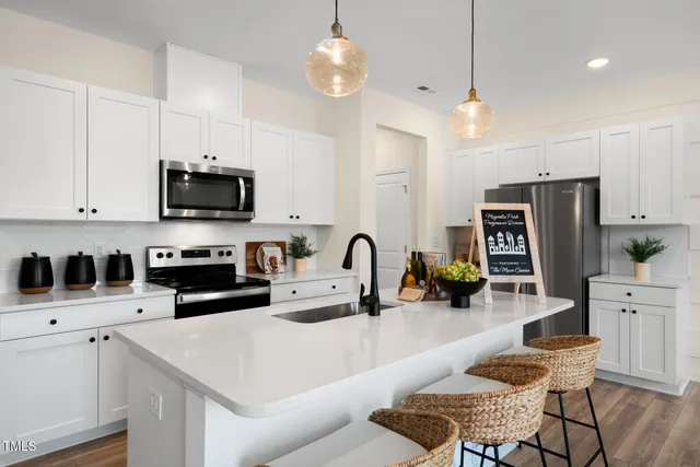 a kitchen with stainless steel appliances kitchen island granite countertop a stove a sink a refrigerator a microwave a dining table and chairs with wooden floor