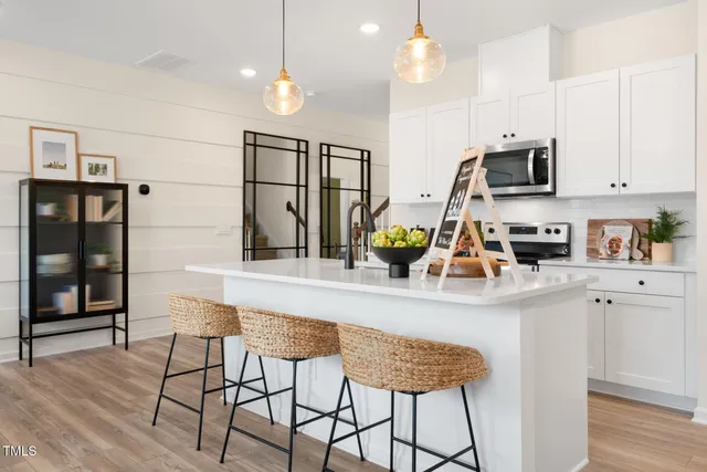 a kitchen with stainless steel appliances granite countertop a refrigerator a sink dishwasher a dining table and chairs with wooden floor