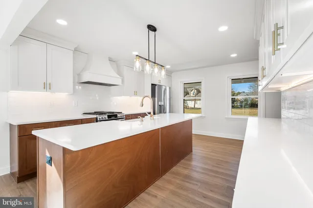 a kitchen with stainless steel appliances granite countertop a sink a stove a refrigerator and island with wooden floor