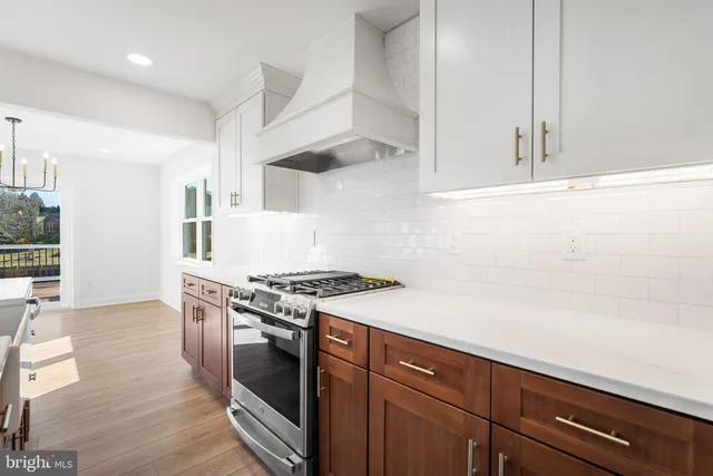 a kitchen with stainless steel appliances a stove and white cabinets with wooden floor