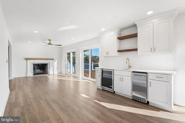 a kitchen with stainless steel appliances granite countertop a stove top oven a sink and white cabinets with wooden floor