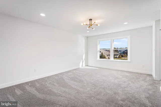 an empty room with windows and chandelier fan