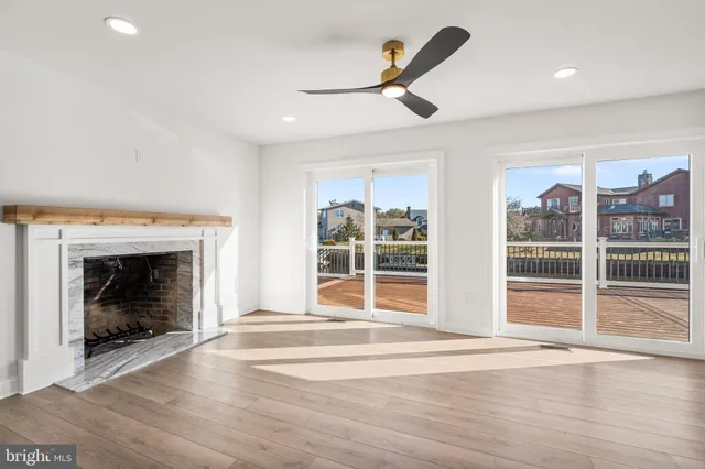 a view of an empty room with wooden floor fireplace and a window