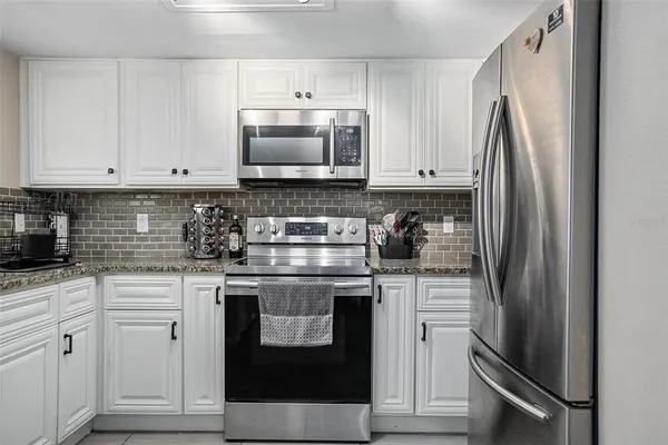 a kitchen with white cabinets and stainless steel appliances