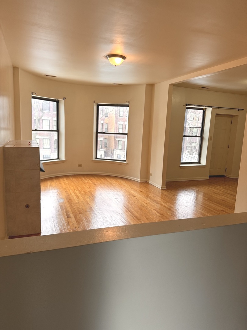 4615 South Michigan Avenue, Unit 2S Chicago, IL 60653 - Photo 3 of 26 a view of an empty room with wooden floor and a window
