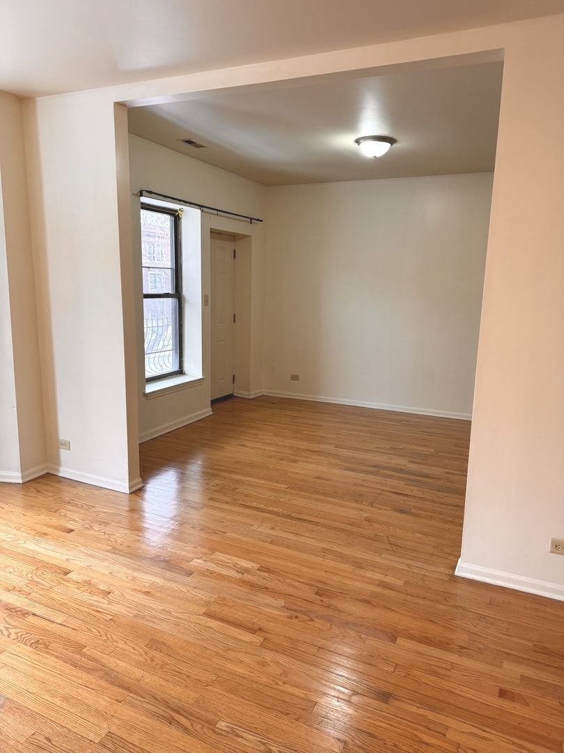 4615 South Michigan Avenue, Unit 2S Chicago, IL 60653 - Photo 9 of 26 a view of an empty room with wooden floor and a window
