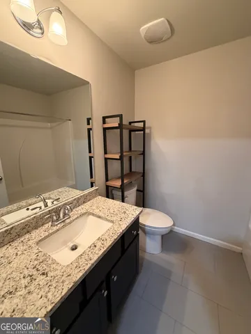 a bathroom with a granite countertop sink a toilet and mirror
