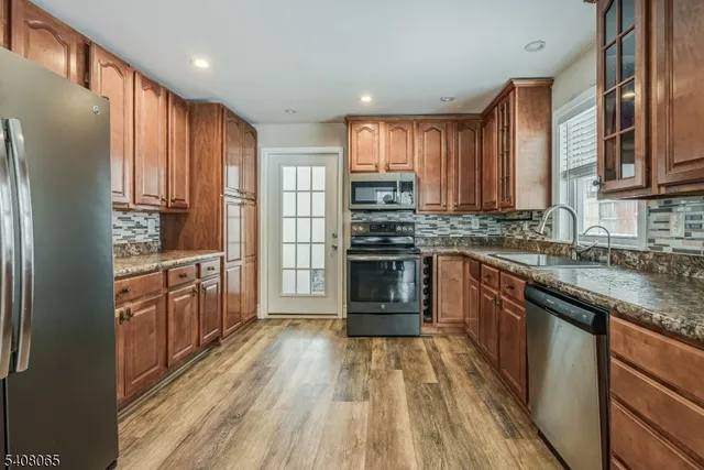 a kitchen with stainless steel appliances granite countertop a refrigerator a sink dishwasher a stove with wooden cabinets and floor