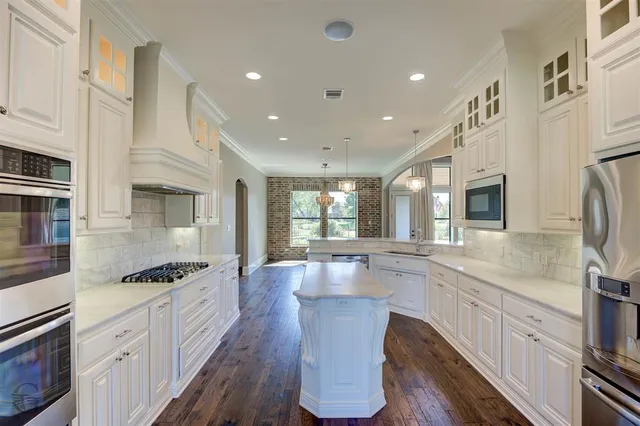 a large kitchen with stainless steel appliances kitchen island granite countertop a sink and cabinets