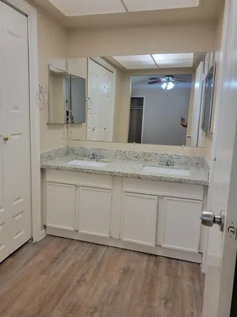 an empty room with wooden floor fan and windows