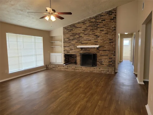 an empty room with wooden floor fireplace and windows