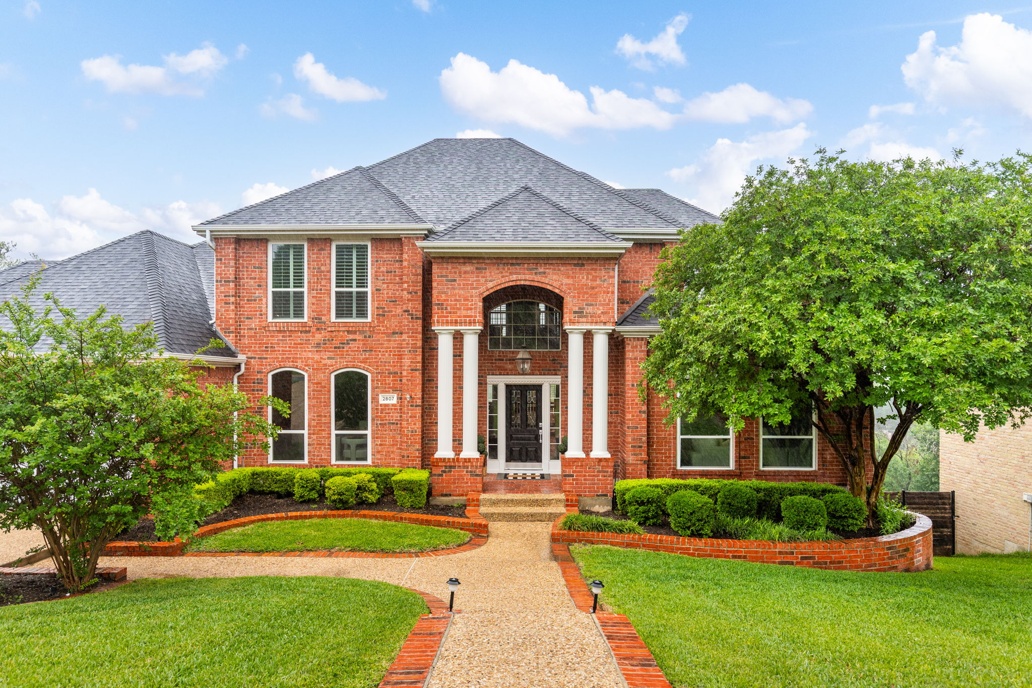 2807 Round Table Road Austin, TX 78746 - Photo 39 of 40 Traditional red brick exterior featuring a multi-gabled roofline and a columned entryway