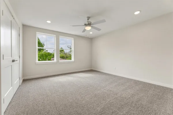 an empty room with windows and ceiling fan