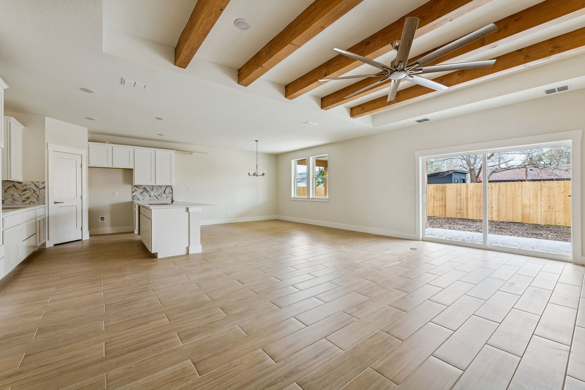 1412 Kent Street Taylor, TX 76574 - Photo 3 of 12 Living room open to kitchen and dining. Wood like hard tile for easy maintenance. Large ceiling fan to stay cool. Beamed ceiling.