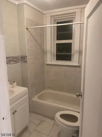 a bathroom with a granite countertop bathtub shower sink vanity and toilet