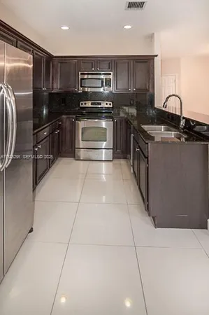 a kitchen with stainless steel appliances granite countertop a sink and a stove top oven