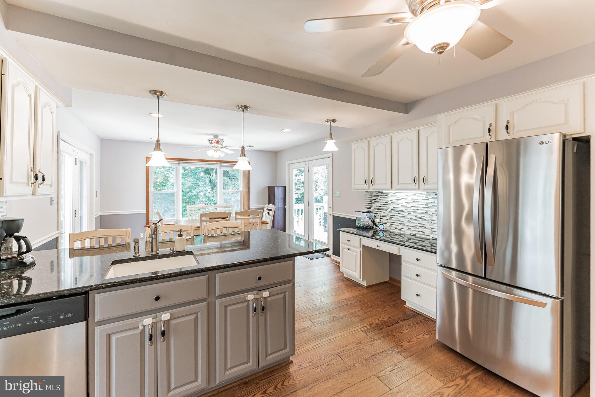 1070 Dale Road Media, PA 19063 - Photo 15 of 40 a kitchen with stainless steel appliances granite countertop a refrigerator a sink dishwasher a stove and a dining table with wooden floor