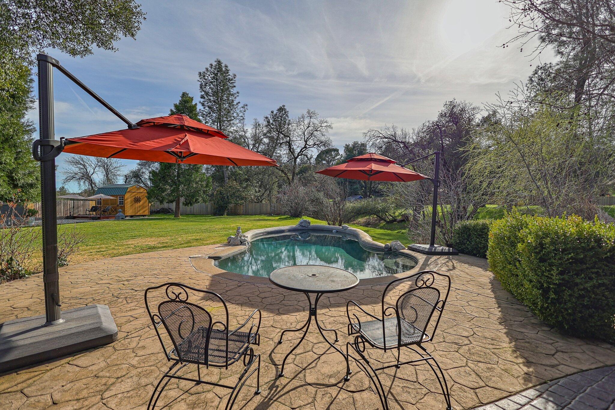 21365 Dersch Road Anderson, CA 96007 - Photo 32 of 55 a view of a swimming pool with a table and chairs under an umbrella