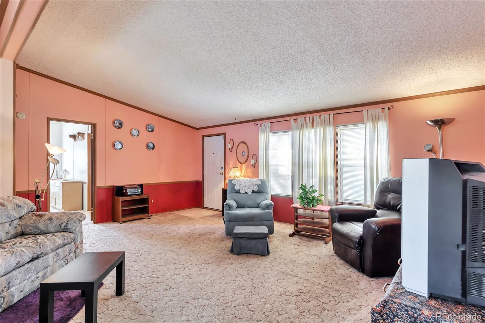 7702 Hart Street Fort Lupton, CO 80621 - Photo 5 of 25 a living room with furniture and a large window