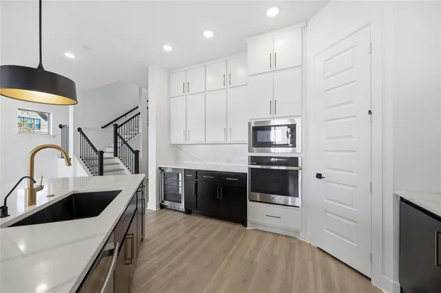 a kitchen with stainless steel appliances granite countertop a refrigerator a oven and a wooden floor