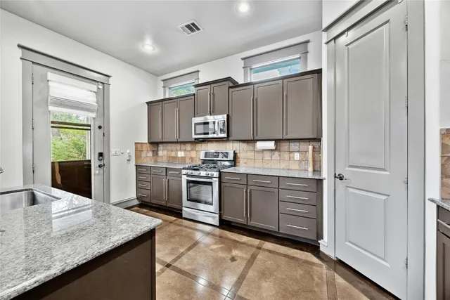 a kitchen with kitchen island granite countertop a stove refrigerator and sink