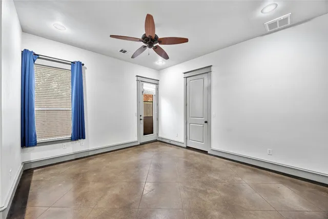 an empty room with ceiling fan and windows