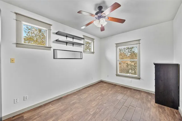 a view of an empty room with a window and wooden floor