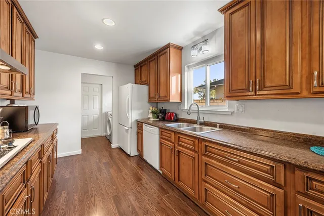 a kitchen with a refrigerator a sink and wooden floors