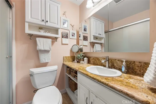 a bathroom with a granite countertop toilet sink and mirror
