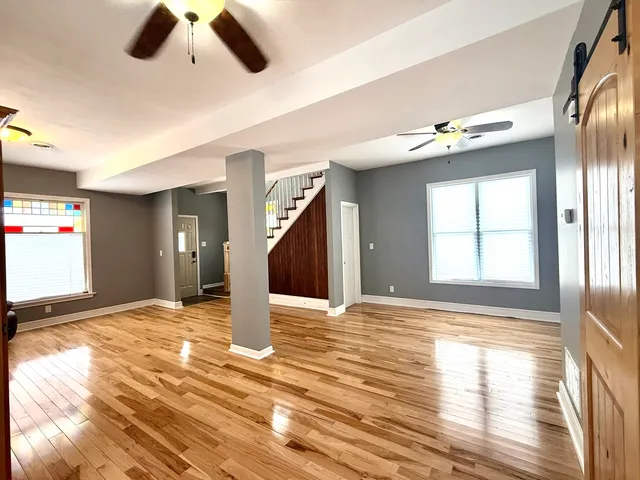 a view of an empty room with window and wooden floor
