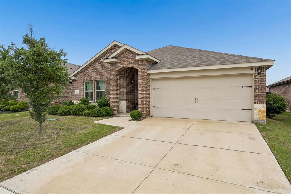 1107 Ringgold Road Forney, TX 75126 - Photo 1 of 27 Brick facade home featuring an arched entryway, attached garage, concrete driveway, and manicured landscaping